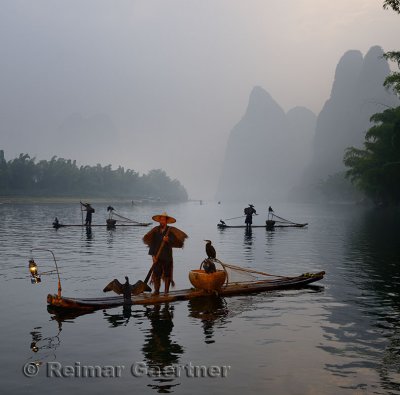 Cormorant fishermen in bamboo rafts at sunrise on the Li river with Karst mountain peaks near Xingping China