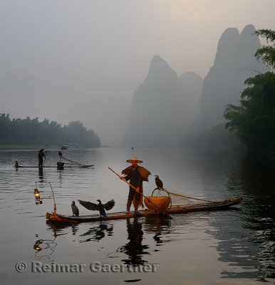 Cormorant fishermen paddling bamboo rafts at dawn on the Li river with Karst mountain peaks near Xingping China