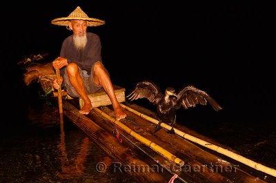 Cormorant fisherman and bird reflected in the Li river at night from a bamboo raft Huangbutan China