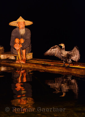 Cormorant fisherman and bird reflected in the Li river at night from a bamboo raft Huangbutan China