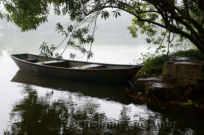 Steel boat in rain moored at Three Pools Mirroring the Moon Island West Lake Hangzhou China