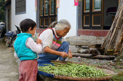 Grandson with lolipop and Grandmother trimming beans in Shangshe village on Fengle lake Huangshan China