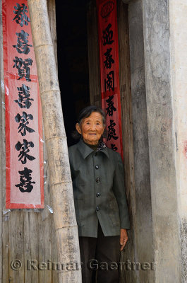 Elderly woman standing in doorway in ancient Shangshe village on Fengle lake Huangshan China