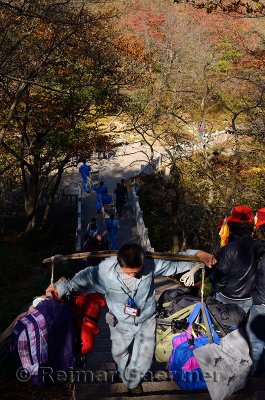 Porters carrying people and bags on the steps of Huangshan mountain China