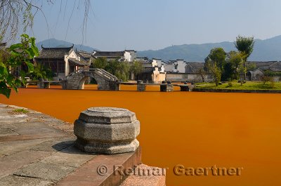 Stone steps and bridge with bright red algae scum on Longxi river in Chengkan village China