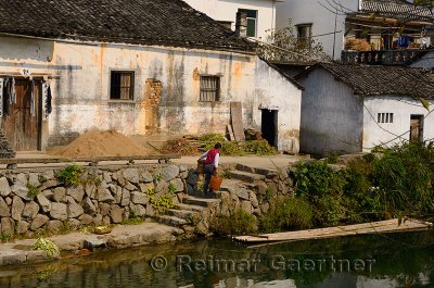 Woman carrying buckets up steps from the Longxi river in Chengkan village China