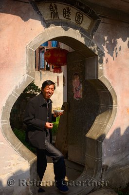 Man eating lunch walking through unique stone doorframe in ancient Chengkan village China