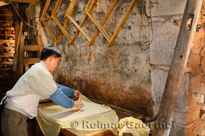 Chinese worker unwrapping pressed firm tofu in a shop in ancient Chengkan village China