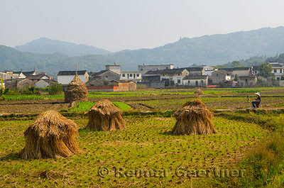 Young female art student painting haystacks and Hui style houses in farm field at Yanggancun village China