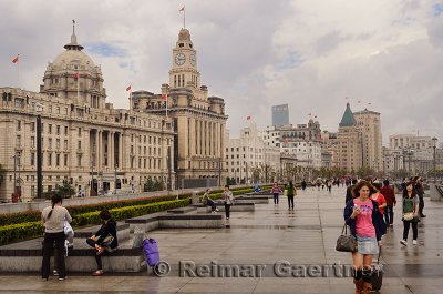 Tourists walking on a wet Bund after a rainstorm with old buildings in Shanghai China