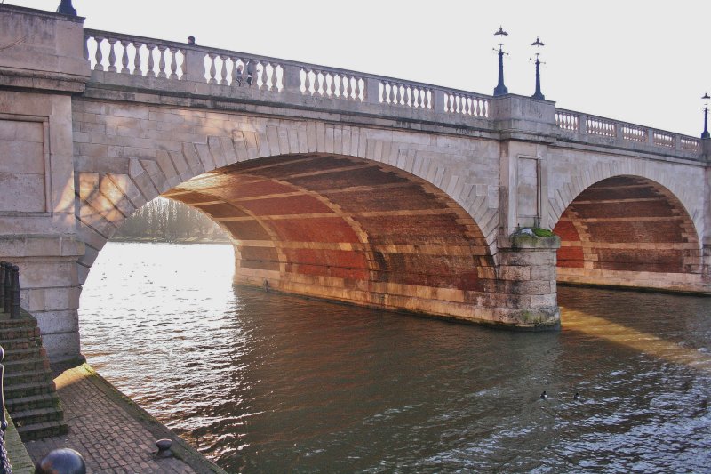 The setting sun shining under the bridge.