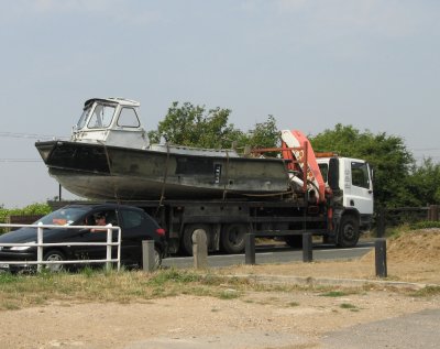 Boat  leaving the island on the back of a lorry.