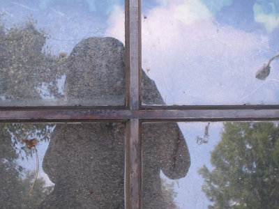 shadowed self portrait in a dirty, thrown-away window