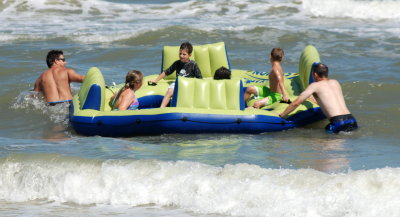 Jon and John pull the raft over the waves as Carter, Brooks, Paige, and Kylie ride