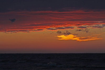 Sun resting in a cloud before setting on Green Bay