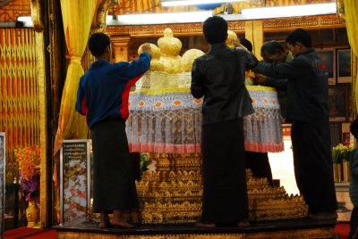 Men (only men...) add gold leaf to statues of Buddha, which are now round in shape as a reult.