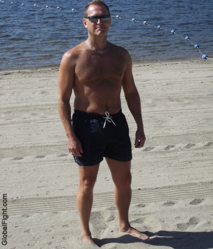 a muscled daddy hot older dude standing on beach.jpg