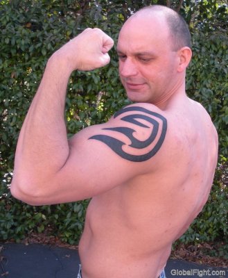man flexing arms biceps big shoulder tattoo.jpg