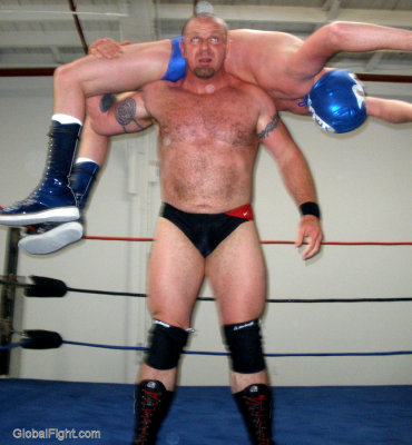 big brutish man lifting wrestler overhead backbreaker application.jpg
