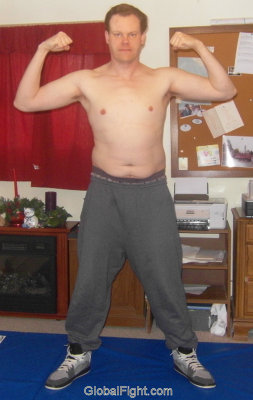 guy posing sweat pants wrestling mats flexing arms biceps.jpg