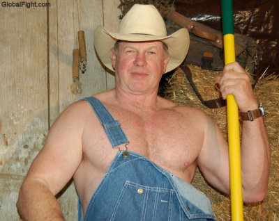 handsome cowboy man denim overalls shoveling barn.jpg
