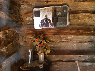 Photographer in log cabin looking glass