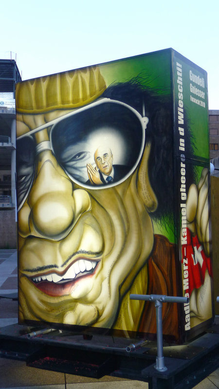 A weird three-dimensional billboard that looked like Muammar Gaddafi with a reflection in his sunglasses of a man praying.