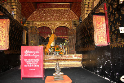 Interior of the temple adorned in gold, red and black and a Buddha shrine.