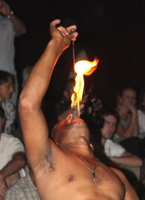 Close-up of him swallowing the torch with flames coming from his mouth.