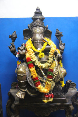 An elephant statue with flowered leis around its neck.
