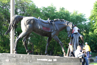 Statue of a horse in the park with kids climbing on it.