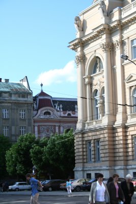 Corner view of Franko Lviv University with people strolling around in front of it.