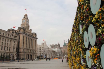 Flowered wall with spotlights at the Bund with the Shanghai Customs House in the background.