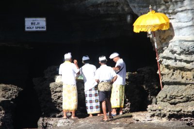 Holy men in front of the holy spring at Tanah Lot temple.