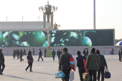 The pedestrians in the square seem oblivious to the huge images on the screen
