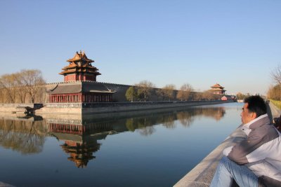 Moat surrounding the Forbidden City with a Chinese man contemplating the Northwest Tower.