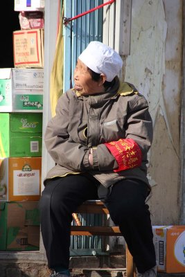 Old Chinese woman sitting in front of a shop in Beijing.
