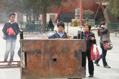 Buddhist worshippers praying and making offerings of incense.