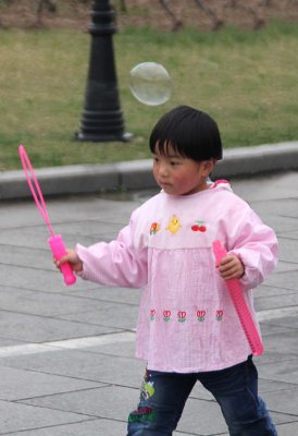 A cute Chinese girl making bubbles in Xian.