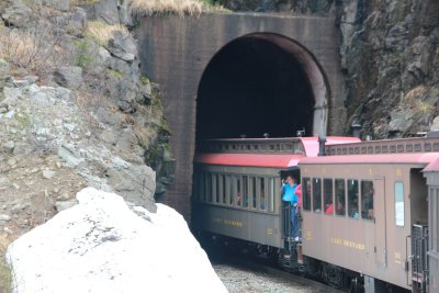 View of the White Pass train cars entering the tunnel with tourists snapping pictures.