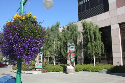 Some native Alaskan totem poles and a gorgeous hanging basket in front of this Anchorage building.