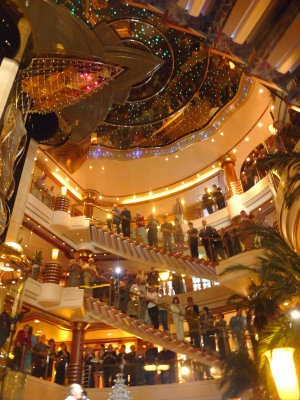 Passengers on the staircases and different decks watching the festivities on deck 5 below.