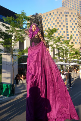 A chic woman on stilts with a rose dress and hair. She looked a bit like Cher.