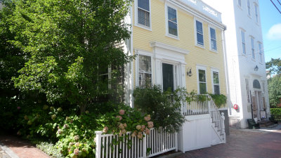 A yellow house with hydrangeas in front.