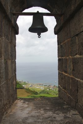Bell at the Brimstone Hill Fortress with a view of the Caribbean Sea in the background.