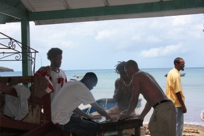 A competitive game of dominoes was taking place in back of the souvenir stand.