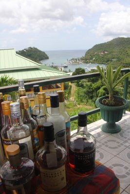 A well stocked bar with St. Lucian rum with a view of Marigot Bay in the background.