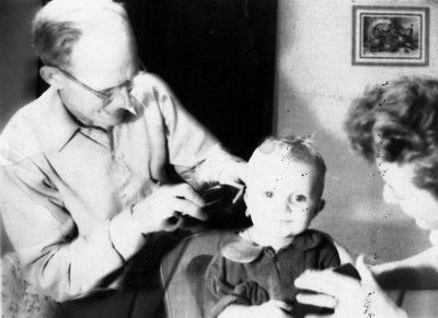 Haskell Hall Sr. giving haircut to Reggie Hall -- 1953