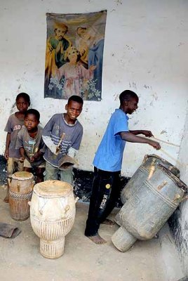 Priest Kwabena Adade´s children play the drums under a poster of the Holy Family.