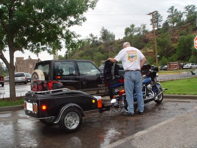 SANDY GETS HIS HARLEY AND TRAILER READY TO LEAVE A WET HOT SPRINGS, SD FOR THEIR TRIP TO YELLOWSTONE